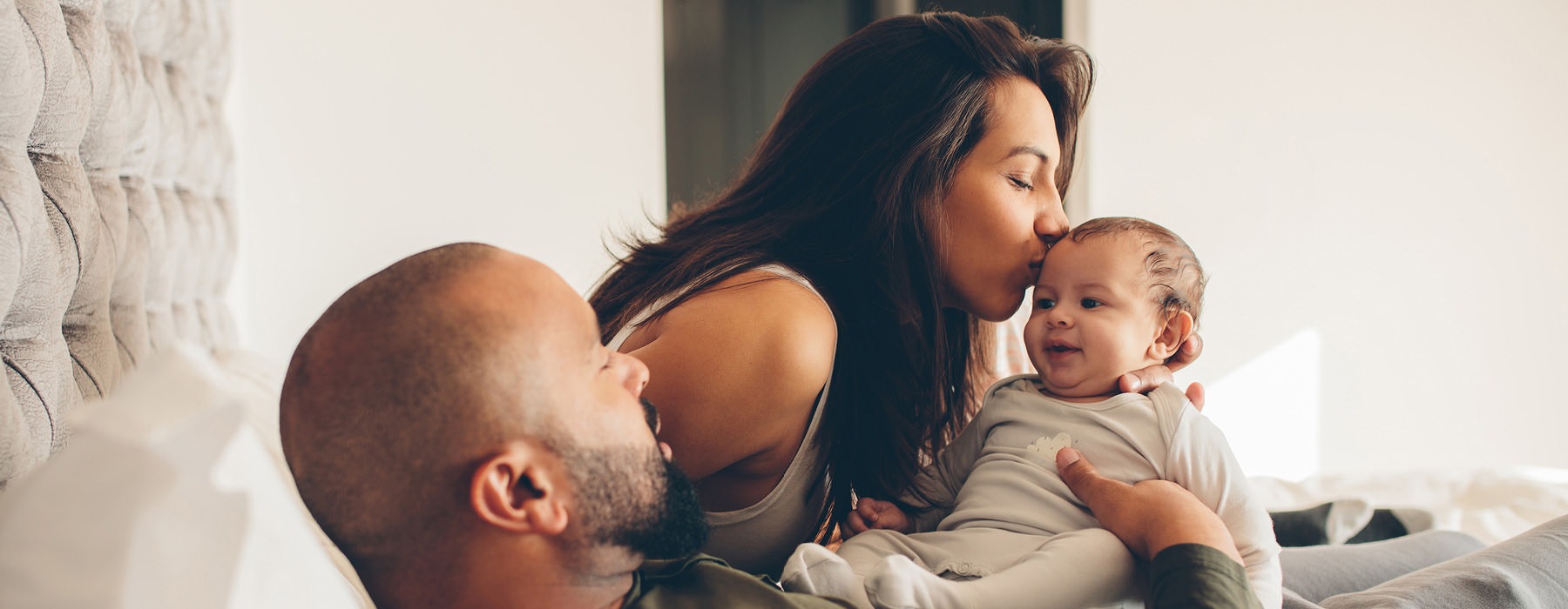 loving parents hold their baby on their bed